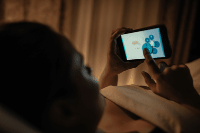 Obrázek osoby používající svůj smartphone v posteli