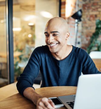 smiling businessman with laptop at office cafeteria 875593414 5c476f5cc9e77c0001ce026c