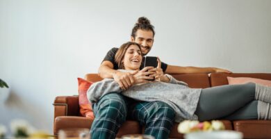 young couple with smart phone relaxing on sofa 974230862 5c4b4d5ec9e77c00013801fc