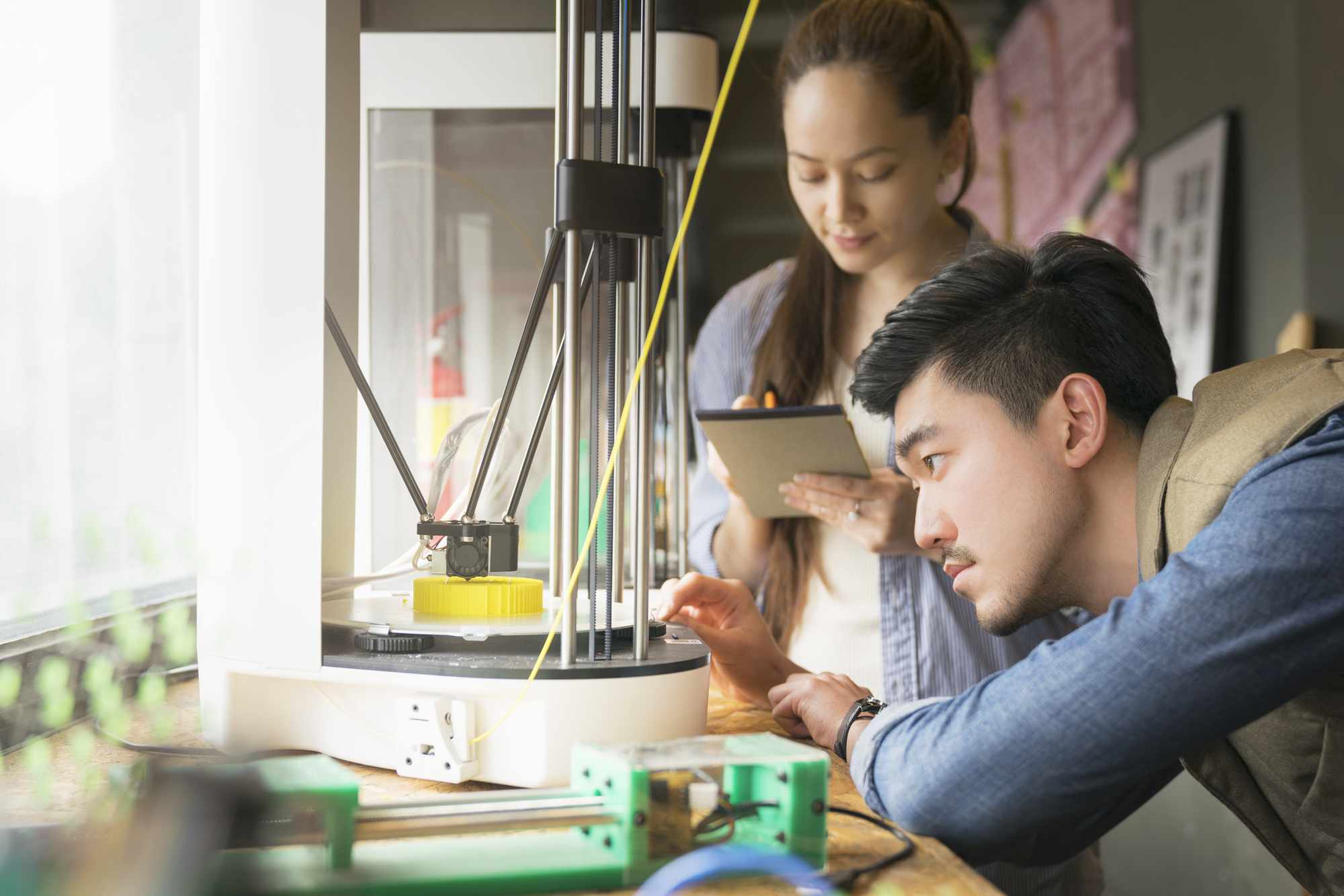 Dva lidé pracující s 3D tiskárnou.