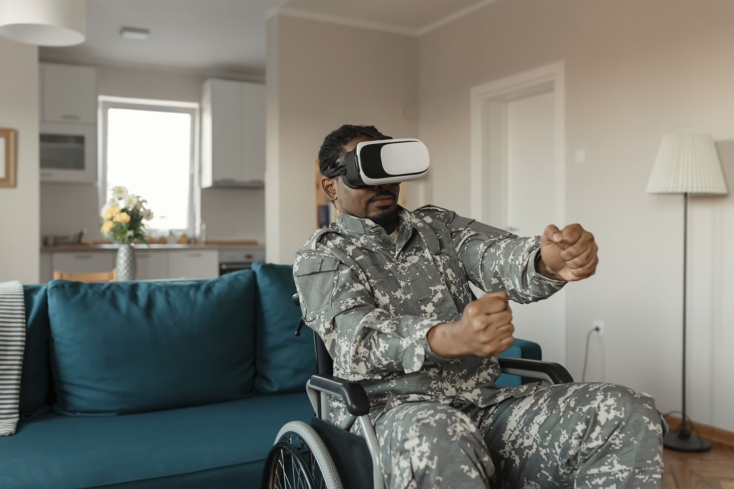 Voják v uniformě na invalidním vozíku s brýlemi pro VR a interagující s tím, co vidí.